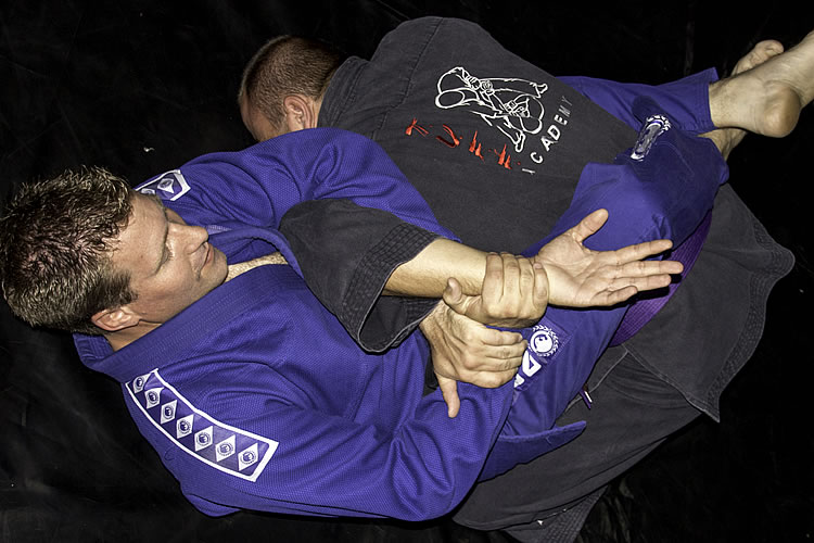 Two students rolling in gi during a Brazilian Jiu-Jitsu class